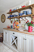 Assorted cups and bowls on wooden shelves above freestanding dresser in Pavilion Grey Victorian cottage Midhurst West Sussex UK
