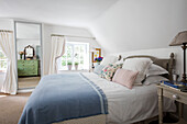 Hellblaue Decke auf einem Doppelbett in einem hellen Schlafzimmer in einem Cottage in Surrey UK