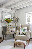 Armchair with parrot cushion and painted antique chest in Surrey cottage UK