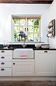 Butler sink and crockery at window in Surrey cottage UK
