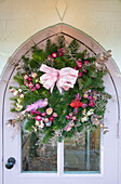 Christmas wreath with pink ribbon on arched front door Surrey UK