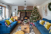 Blaue Sofas mit senfgelben Kissen und Weihnachtsbaum in einem Haus in Surrey, UK
