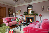 PInk sofas and lit fire in Grade II listed Georgian country house West Sussex UK