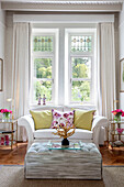 Schnittblumen auf Ottomane mit Zweisitzer-Sofa im Fenster in Wales, UK