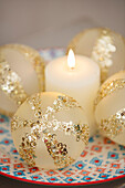 Gold sequinned baubles with lit candle in Hampshire UK