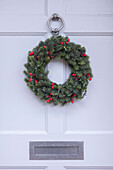Christmas wreath with silver fittings on white front door Hampshire UK