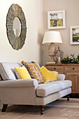 gelbe Kissen auf zweisitzigem Sofa unter Spiegel in Hampshire UK