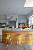 Offene Küche mit hellgrauen Arbeitsflächen und gelben Barhockern Sussex UK