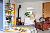 Brown leather armchair and lit fire with shelves Sussex UK