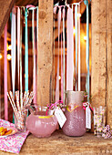 Jugs of pink grapefruit lemonade with drinking straws and ribbon in timber framed barn late summer UK