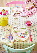Easter eggs on place setting with pink blossom and yellow teapot