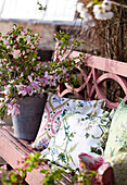 Outdoor spring floral decorations on pink painted garden bench in preparation for an Easter party