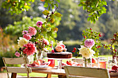 Spätsommerpicknick im Garten mit Kuchen, Obst und Blumen