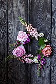 Foxglove and peony wreath on a wooden background