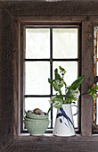 Kunsthandwerkliche Osterfensterbank mit Tulpenkrug und Schalenstapel mit gesprenkelten Eiern