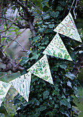 Floral bunting hanging in a garden against some ivy on a tree trunk