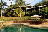 Tin roofed and timber house in tropical garden with swimming pool