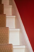Details einer weiß gestrichenen Treppe mit Teppichläufer
