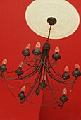 Red painted ceiling light with neutral ceiling rose and large decorative chandelier