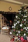 Geschmückter Weihnachtsbaum in einem Wohnzimmer mit einem beleuchteten Feuer