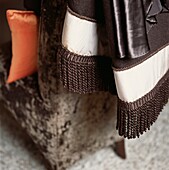 Brown woolen tassel fringe throw on the back of a chair