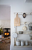 Blick von der Küche mit hängenden Küchenutensilien auf das gemütliche Esszimmer mit beleuchtetem Kamin und Weihnachtsbaum