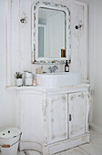 Weißes Badezimmer im skandinavischen Stil, Nahaufnahme mit kunstvoll geschnitztem Waschtisch, weißem Emaillegeschirr und hübschen Kristallwandleuchten
