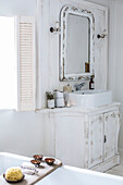 Weißes Badezimmer im skandinavischen Stil, Nahaufnahme mit kunstvoll geschnitztem Waschtisch, weißem Emaillegeschirr und hübschen Kristallwandleuchten