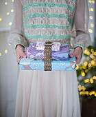 Girl holding gifts wrapped in vintage wallpaper decorated with gold braid