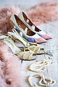 Vintage Schuhe und Schmuck mit rosa Federboa und Perlenkette auf dem Boden
