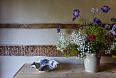 Sideboard with garden flowers in a jug and carved wooden beam