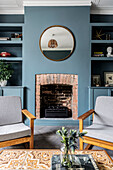 Modern living room with grey armchairs and fireplace on a blue wall
