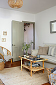 Bambus- und Schilfrohrmöbel, Juteteppich und helles Sofa im Wohnzimmer