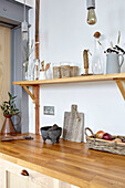 Fitted kitchen with wooden butcher block counter top, above it wooden shelves