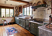 Country kitchen with green cabinets and copper pots on the ceiling