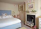 Double bed in cream-coloured room with fireplace, pennant chain above