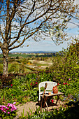 Sitzplatz mit Spaten in sonnigem Garten mit Landschaftsblick