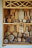 Collection of wooden chopping boards and other kitchen utensils on shelves