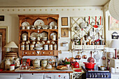 Wooden shelf with storage boxes and crockery, next to it various kitchen utensils on vintage shelf in kitchen
