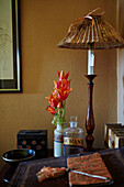 Table lamp and tulips on antique chest of drawers