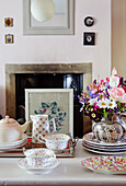 Tea set and bouquet of flowers on table in front of fireplace