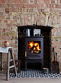 Wood-burning stove with fire, brick chimney and vintage decorations