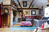 Sofa und Polstercouchtisch vor offenem Backsteinkamin, Kunstwerke an der Wand im Wohnzimmer