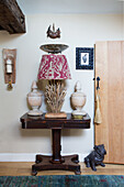 Table lamp with driftwood base between two antique urns on console table
