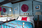 Juju hat on wall above double bed in rustic bedroom