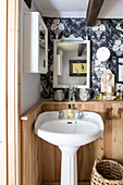 Pedestal washbasin in guest toilet with wooden wainscoting and patterned wallpaper
