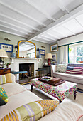 Living room with fireplace, patterned stool and mirror on the mantelpiece