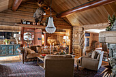 Rustic living room with wooden walls, chandelier and sloping ceiling