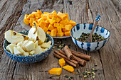 Pieces of pumpkin, apple cubes, pumpkin seeds and cinnamon sticks on wooden table