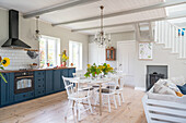 Landhausküche mit blauen Unterschränken und weißem Holztisch mit Stühlen